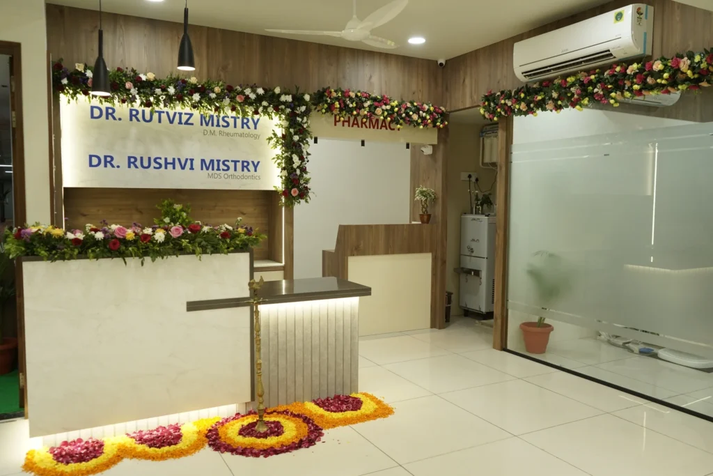 The reception and pharmacy counter decorated with a floral rangoli, below the clinic name boards