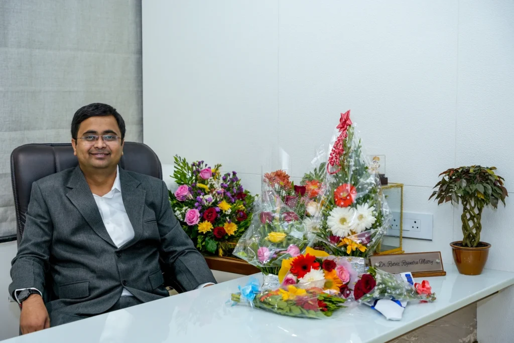 Dr. Rutviz Mistry, Rheumatologist, seated at his desk with bouquets of flowers on the clinic's opening day